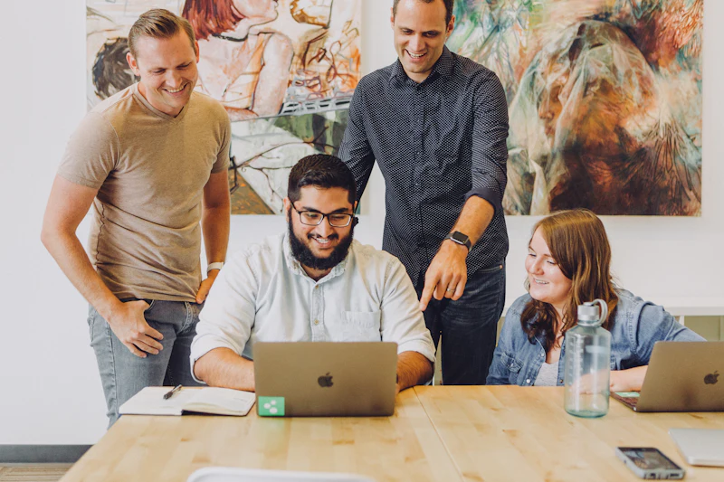 Team talking and laughing around a laptop